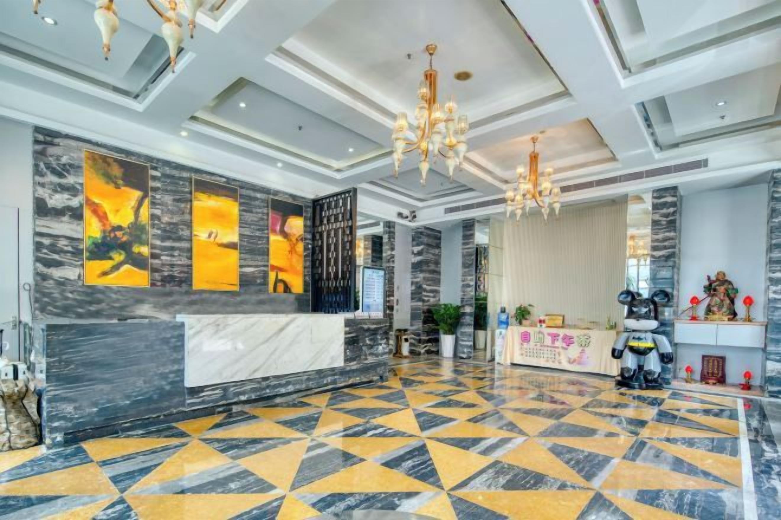 Eine Hotelhalle mit einer Rezeption, einem gemusterten Boden und einer Kristallleuchtre.
