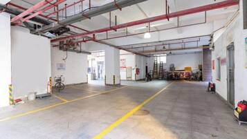 A spacious indoor area with a concrete floor, visible structural beams, and a bicycle parked in the corner.