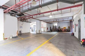 A spacious indoor area with a concrete floor, visible structural beams, and a bicycle parked in the corner. - Xinyi Hotel (Dongguan)
