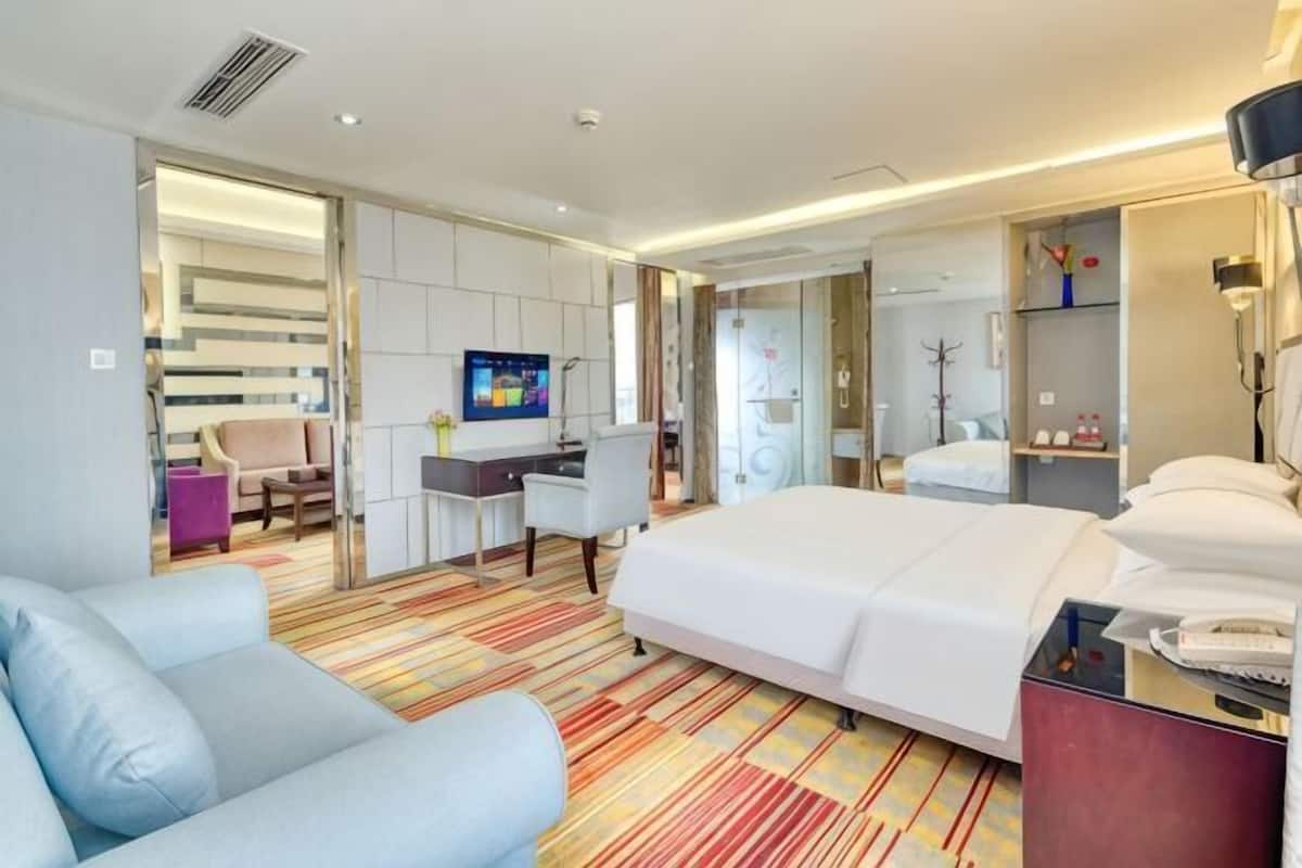 A hotel room with a bed, a desk, a chair, a TV, and a bathroom.