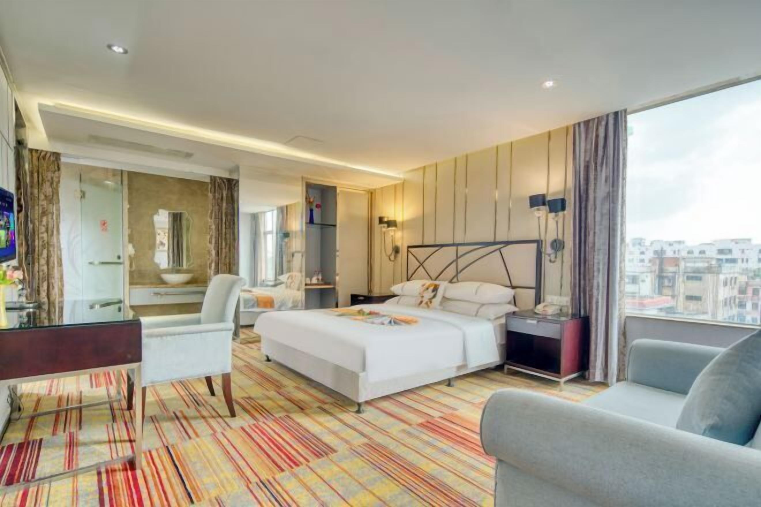 Une chambre d’hôtel moderne avec un grand lit, un bureau, une chaise et un canapé.