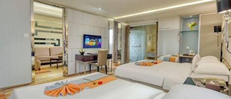 Habitación de hotel con dos camas, un escritorio con una silla, televisión y un baño visible a través de una puerta abierta.