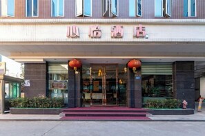 A hotel entrance with a red carpet, glass doors, and two red lanterns above the entrance. - Xinyi Hotel (Dongguan)