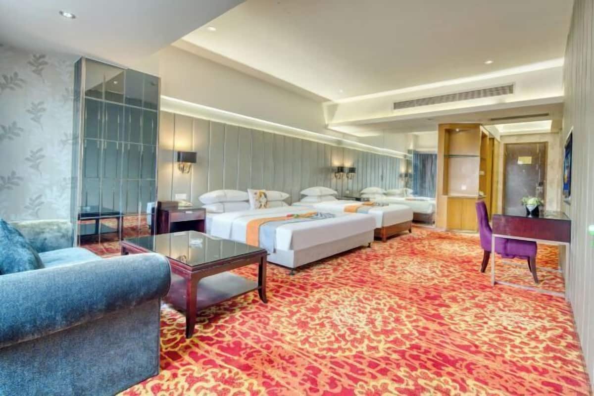 A hotel room with a large bed, a sofa, a desk, and a mirror.