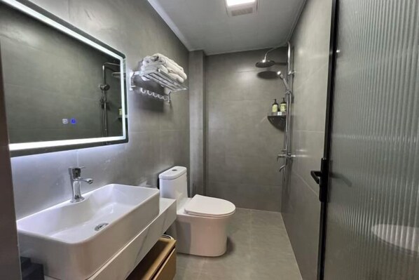 Un baño moderno con un espejo grande, un lavabo, un inodoro y una zona de ducha.