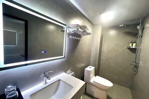 Un baño moderno con un espejo grande, un lavamanos, un inodoro y una ducha.