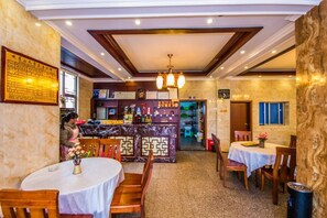 Un restaurante con mesas redondas, una zona de bar y un candelabro.