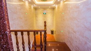 Una escalera de mármol con barandilla de madera que conduce a un rellano.