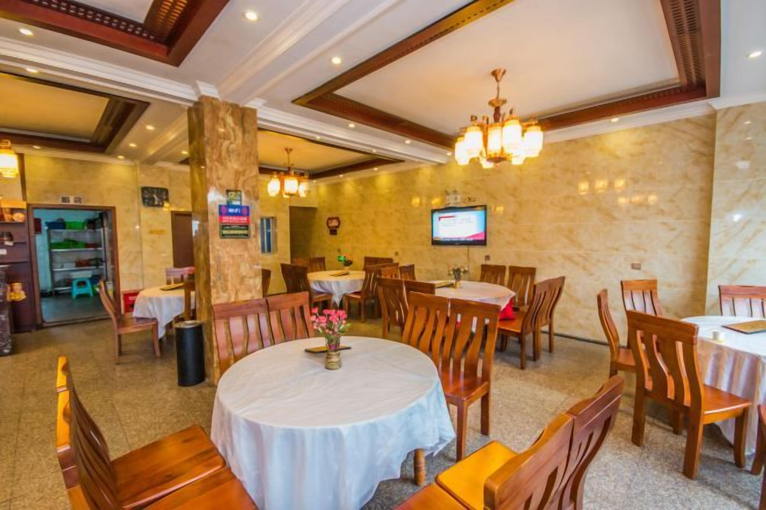 A restaurant with round tables, wooden chairs, and a chandelier.