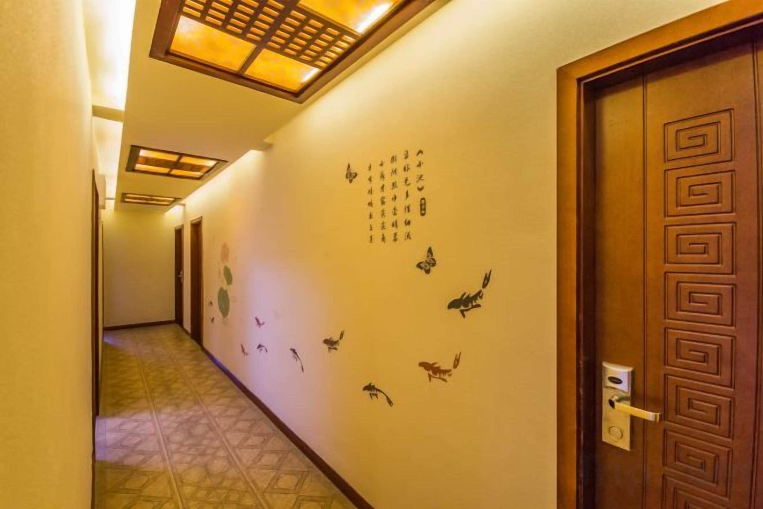 A hotel hallway with a wooden door, a patterned wall, and a tiled floor.