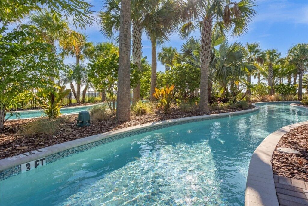 Une piscine aux eaux cristallines, dont la profondeur maximale est indiquée à 3 pieds, entourée de palmiers et d’une végétation tropicale.