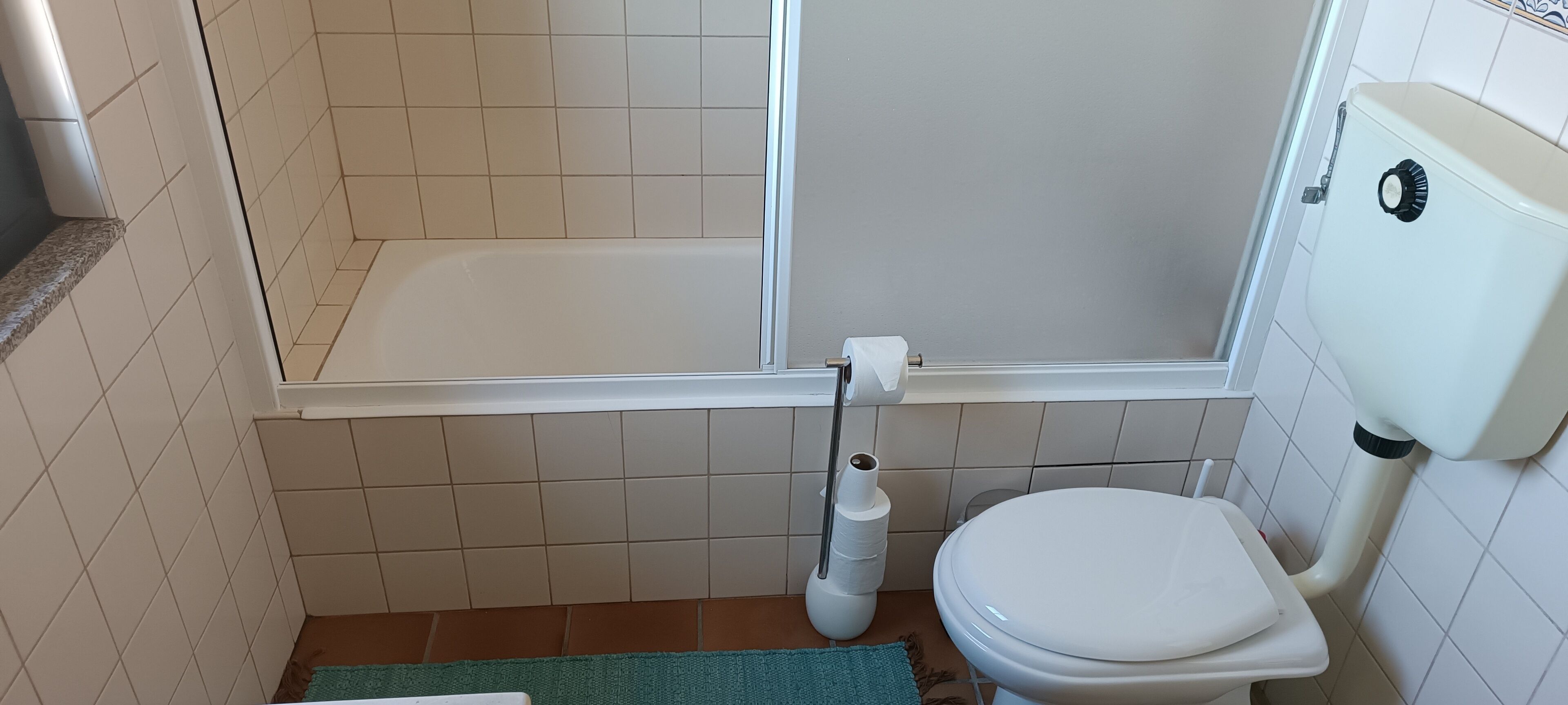 Un baño con bañera, inodoro y dispensador de papel higiénico.