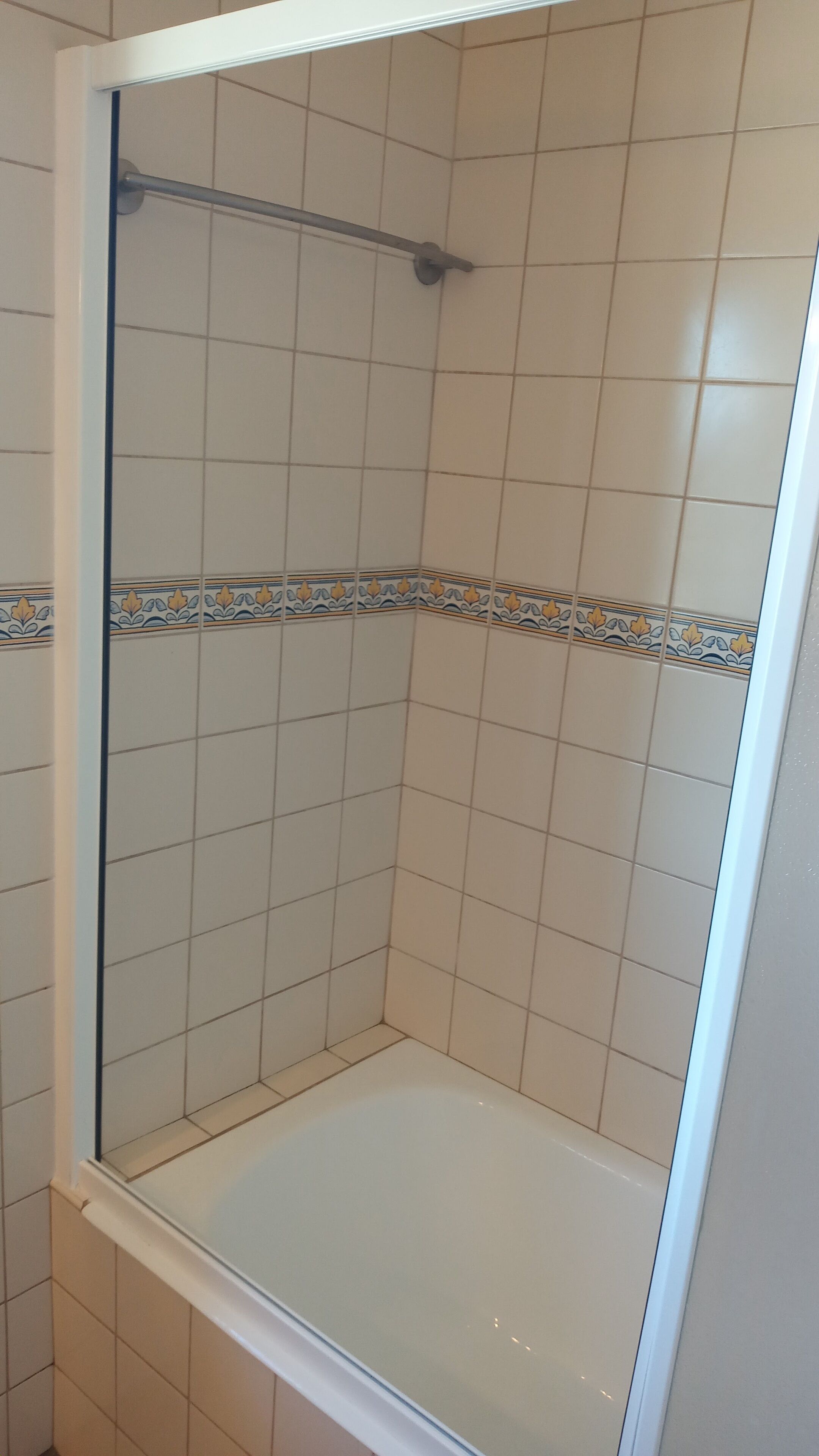 Un baño con cabina de ducha, paredes de azulejos y un detalle decorativo.