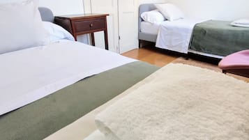 A hotel room with two beds, a small wooden nightstand, a chair, and a green bedspread.