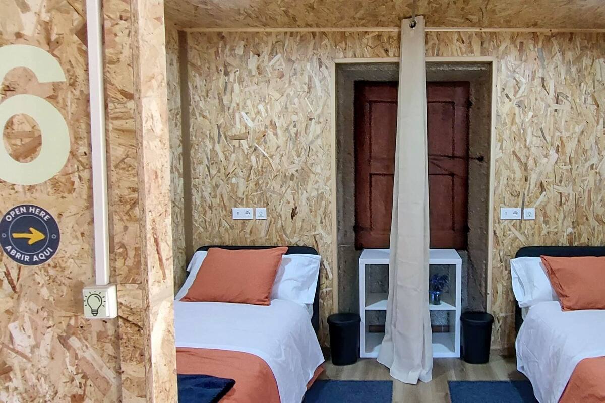 A room with two beds, a wooden wall, and a door.