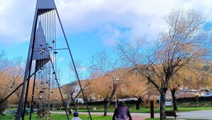 A park with a red pathway, a metal sculpture, and leafless trees. - Donna Nega Guest House  (Caminha)