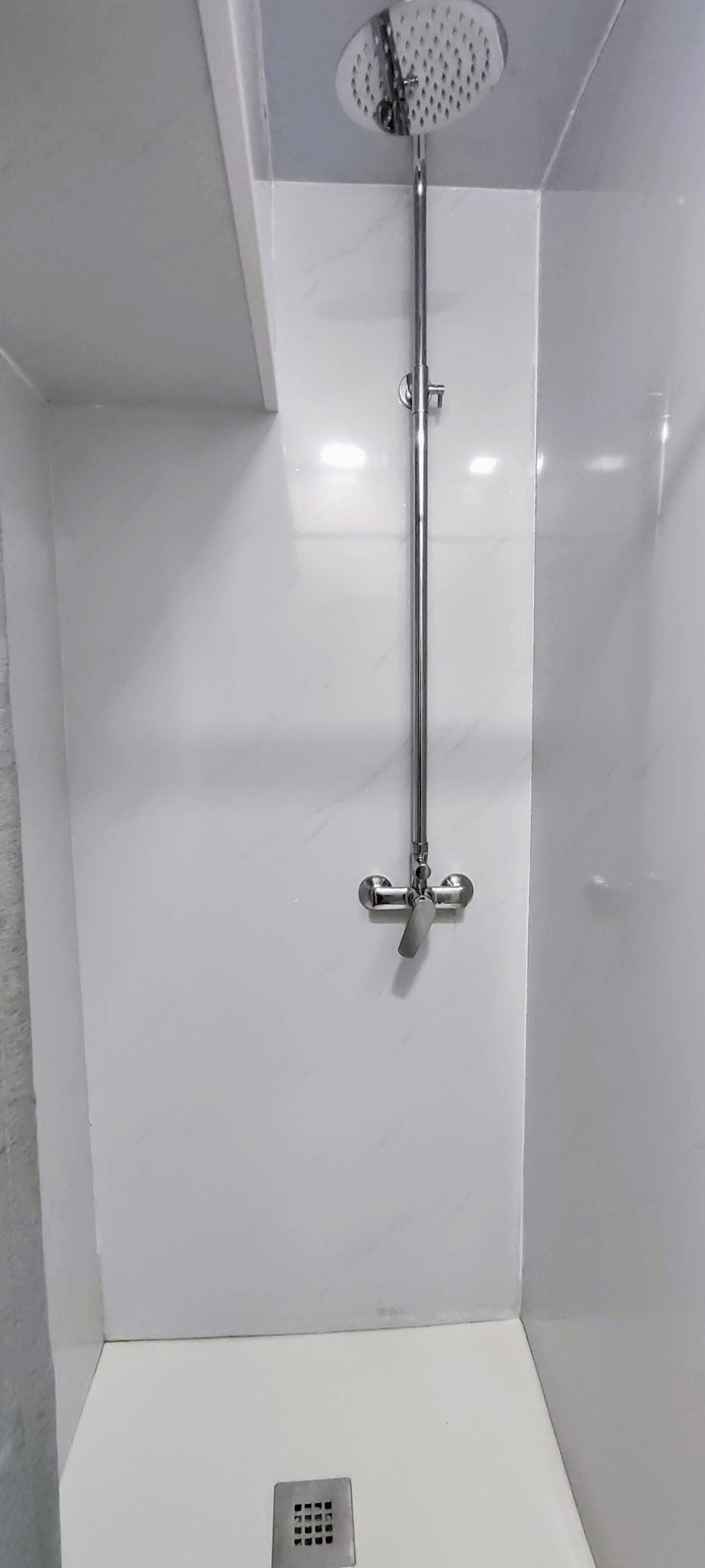 A shower with a handheld showerhead and a wall-mounted faucet.