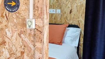 Una habitación con una cama, un interruptor de luz y una puerta con el número 6.