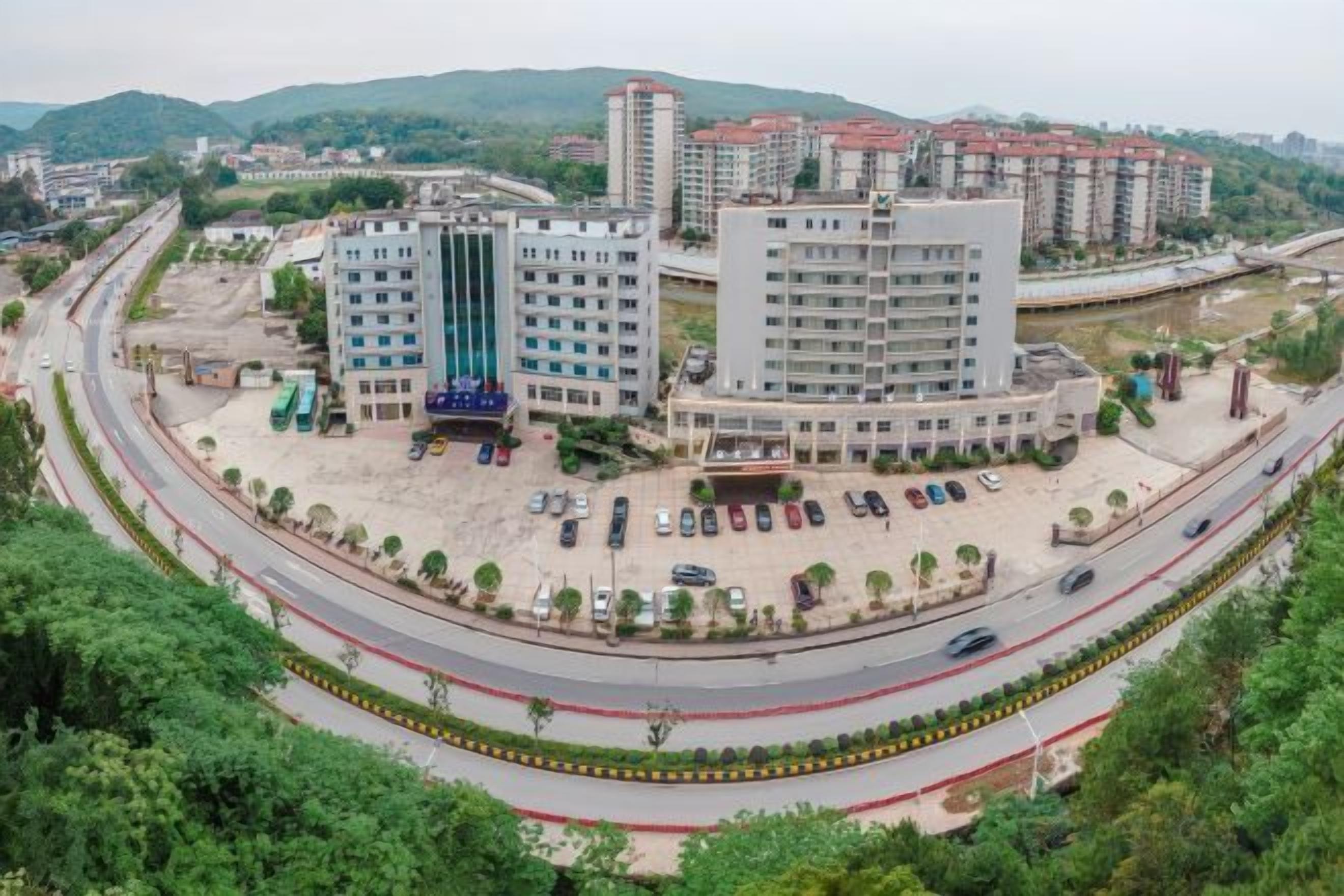 A multi-story building with a central courtyard, surrounded by roads and greenery.