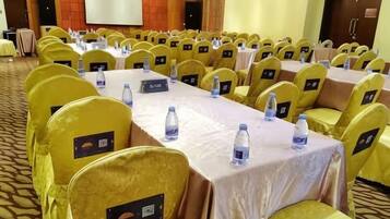 Un salón de conferencias con hileras de sillas amarillas, mesas con tarjetas de identificación y botellas de agua.