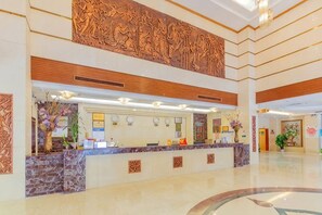 A hotel reception area with a marble counter, a large decorative wall, and a reception desk.