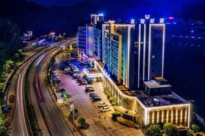 A modern hotel with multiple floors, a parking lot, and a view of the surrounding area.