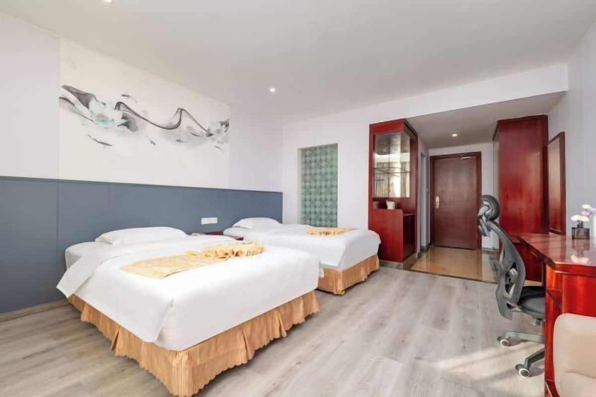 Habitació d'hotel amb dos llits, una taula i una cadira.