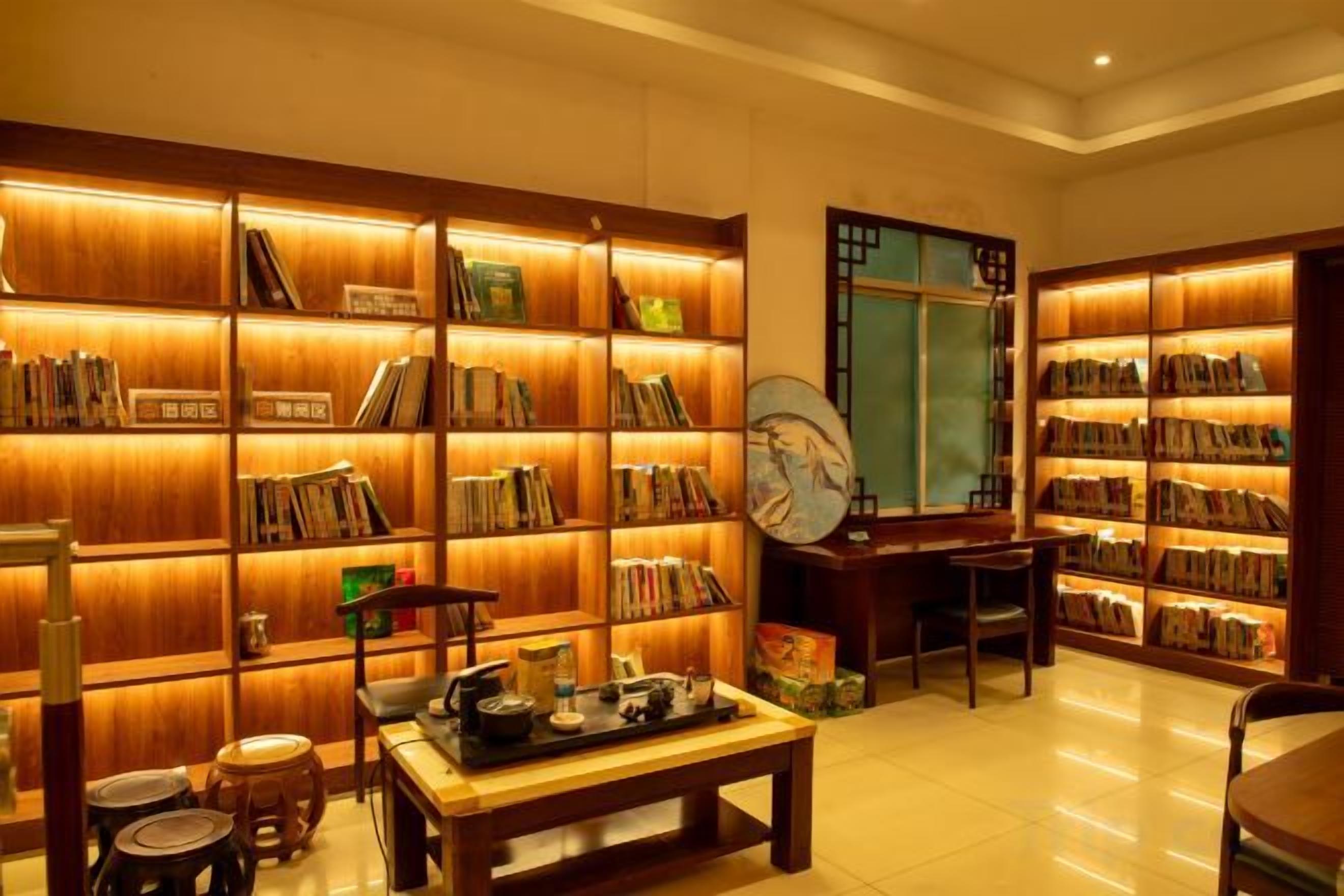 Una biblioteca con estanterías, una mesa con libros y un sillón tradicional.