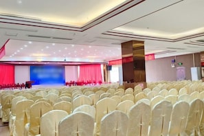 A conference room with rows of chairs, a stage with a blue backdrop, and a podium. - Friendly Hotel (Shaoguan Nanhua Temple) (Shaoguan)