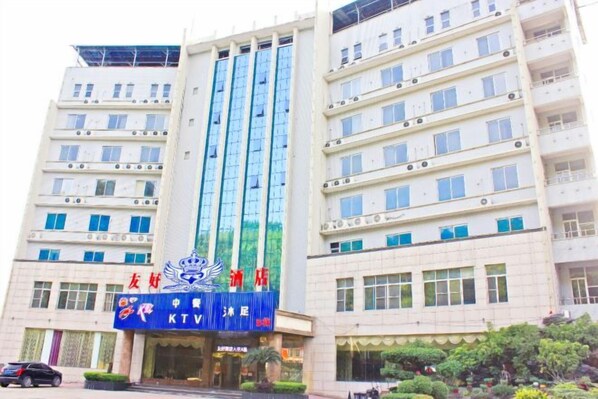 A multi-story hotel with a prominent blue sign at the entrance, multiple balconies, and a series of windows on each floor.