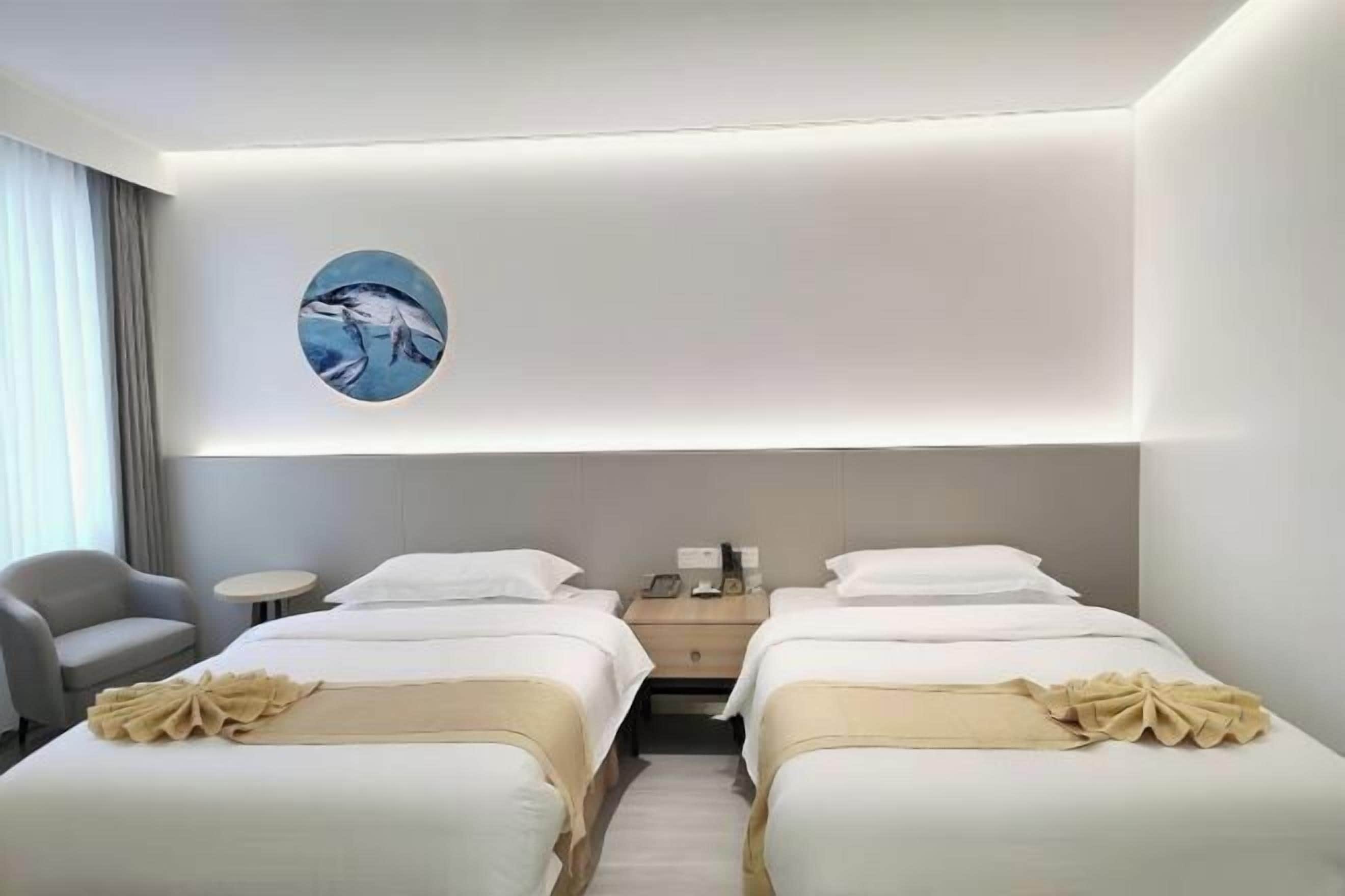 Habitación de hotel con dos camas, una mesita, una silla y una obra de arte en la pared.