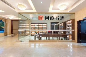 A modern interior with a glass storefront, bookshelves, and a seating area.