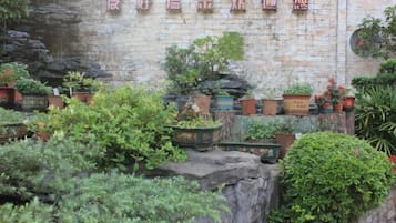 A brick wall with potted plants and a sign with Chinese characters.