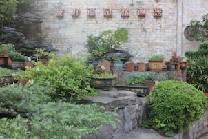 A brick wall with potted plants and a sign with Chinese characters.