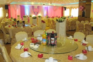 A banquet hall with round tables set for a formal event, featuring glass tops, white tablecloths, and red napkin rings. - Friendly Hotel (Shaoguan Nanhua Temple) (Shaoguan)