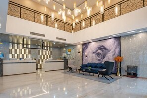 Eine Hotelhalle mit einer Rezeption, einer Sitzgelegenheit und einem großen Wandgemälde.