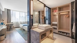A modern hotel room with a large mirror, two sinks, a wooden vanity, a closet, and a seating area with a table and chairs. - Echarm Hotel (Gaoqing Zhongcheng International) (Gaoqing)