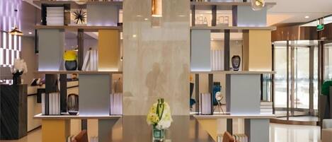 A modern hotel lobby with a central table, seating, and a decorative vase.
