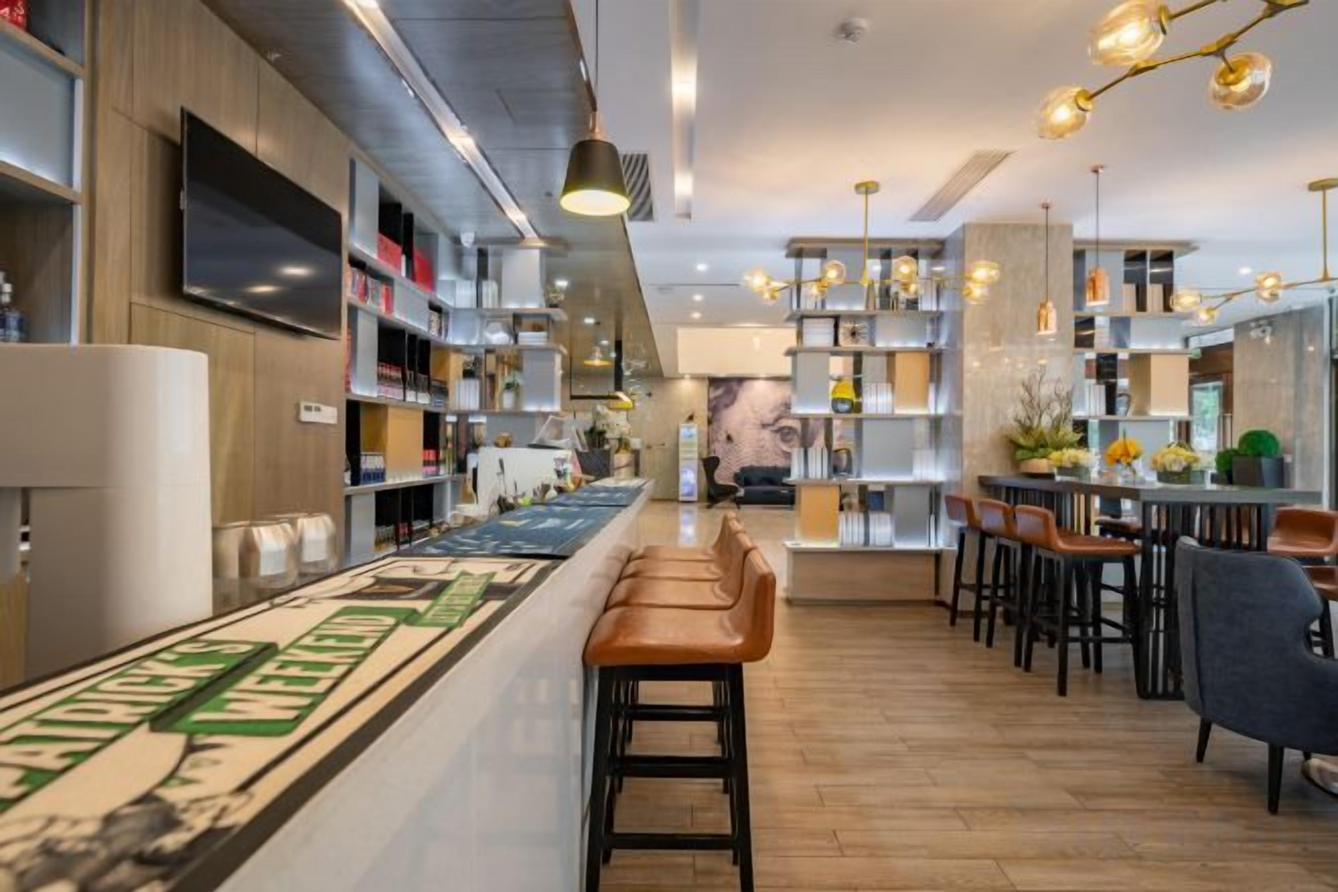 A modern bar area with a long counter, bar stools, and a patterned backsplash.