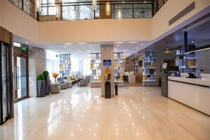 Um saguão de hotel com balcão de recepção, área de estar e escada.