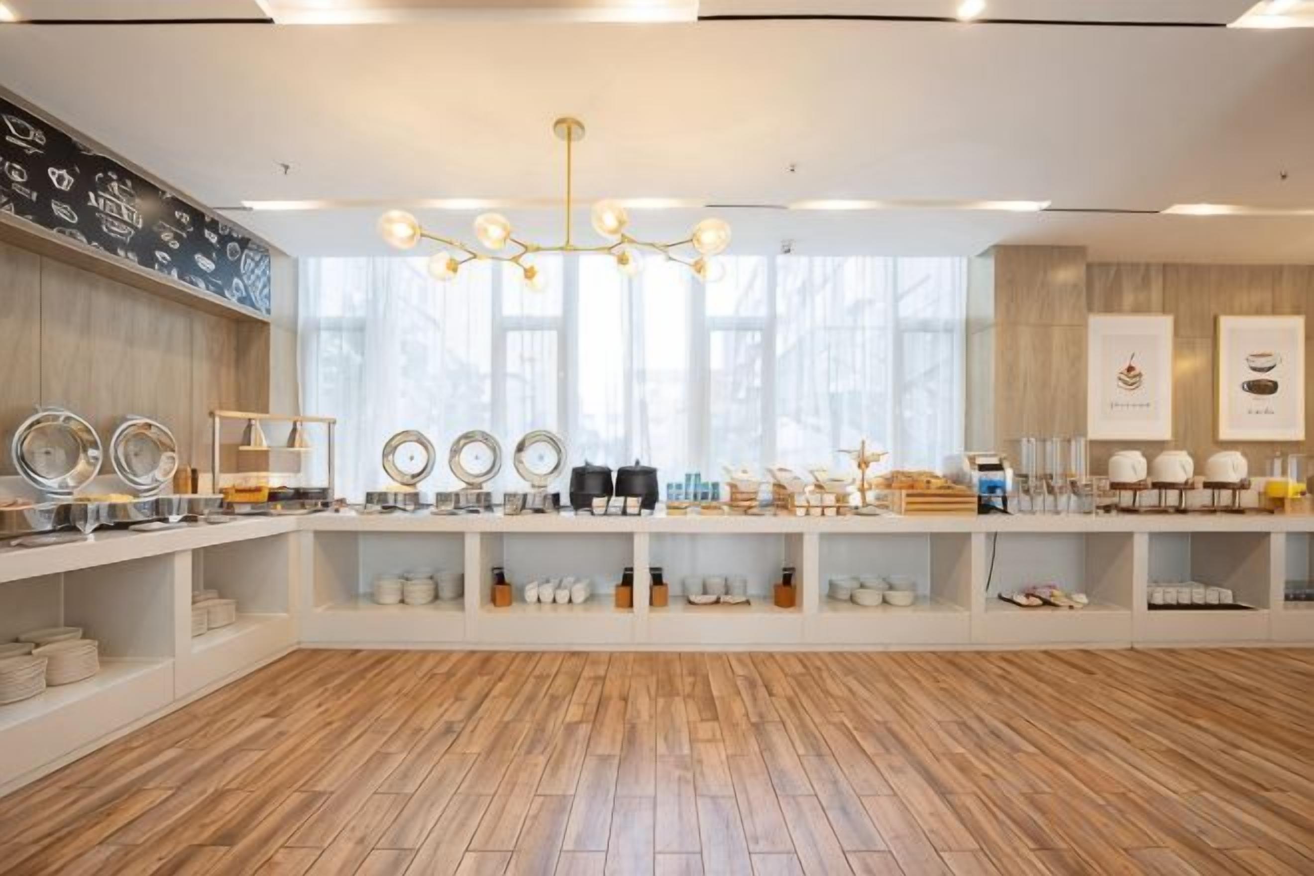 A spacious room with wooden flooring, white shelving units, and a variety of kitchenware displayed on the shelves.