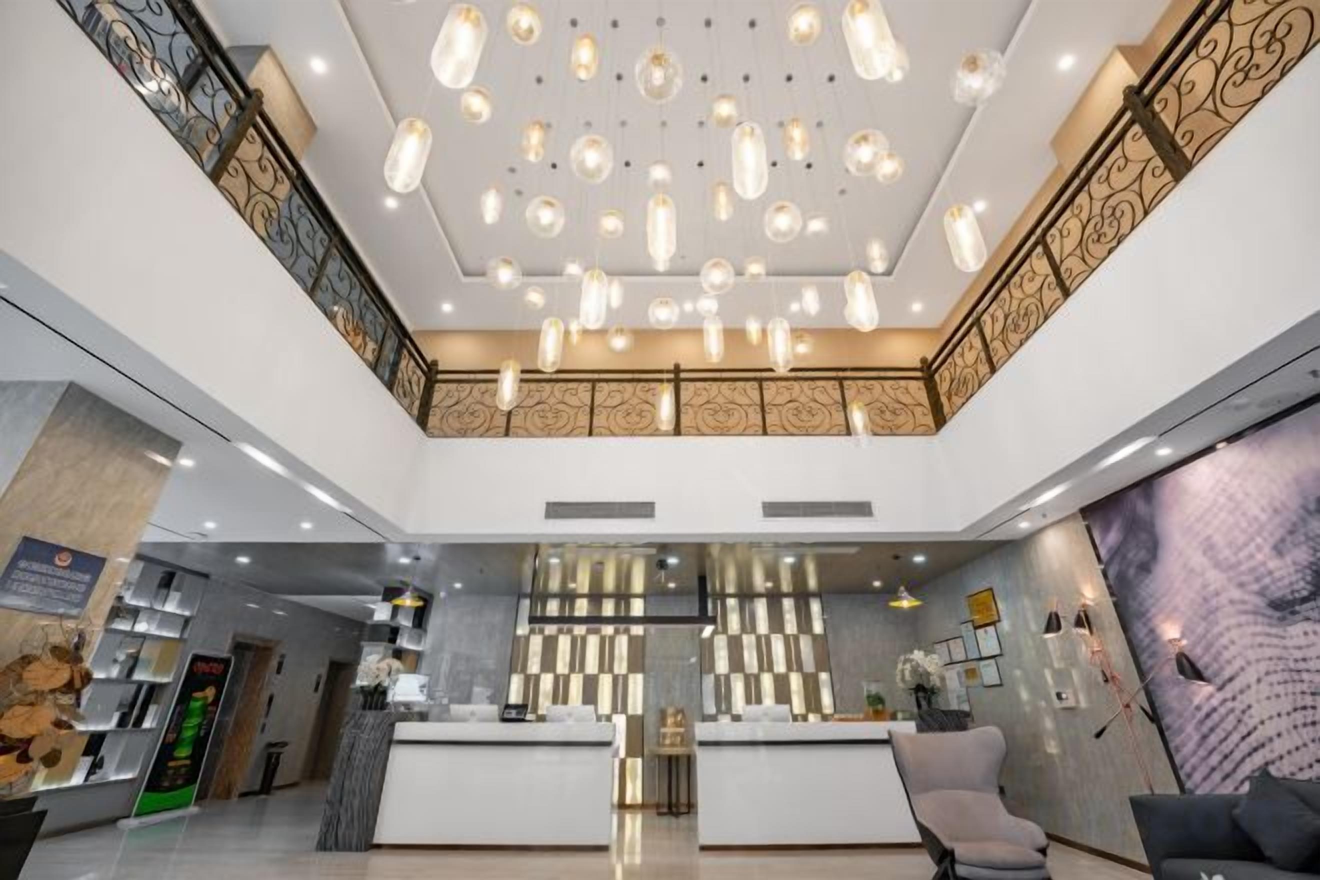 A hotel lobby with a reception desk, seating area, and decorative ceiling lights.