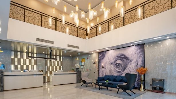 A modern hotel lobby with a reception desk, seating area, and a large wall mural. - Echarm Hotel (Gaoqing Zhongcheng International) (Gaoqing)