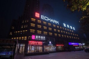 Een meerhoog gebouw met verlichte borden waarop 'ECHARM' en 'Echarm Hotel' staan.