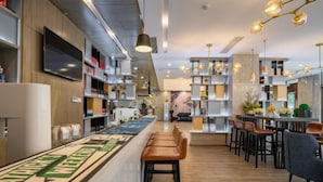 A modern bar area with wooden flooring, bar stools, and shelves with various items. - Echarm Hotel (Gaoqing Zhongcheng International) (Gaoqing)