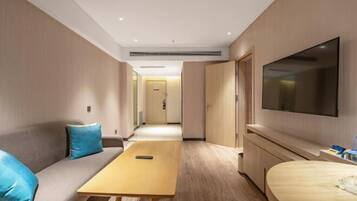 A hotel room with a sofa, a small table, a TV, and a bed.