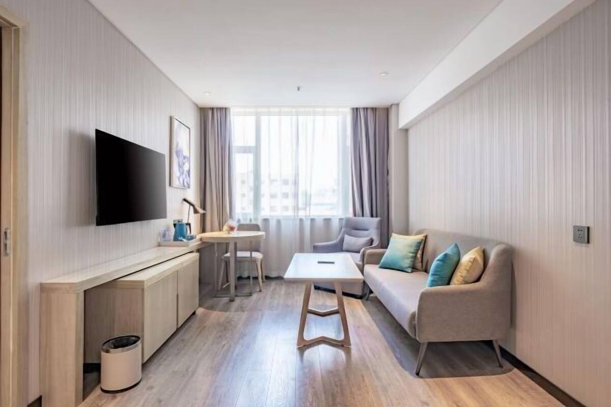 A modern living room with a flat-screen TV, a sofa, a coffee table, and a dining area.