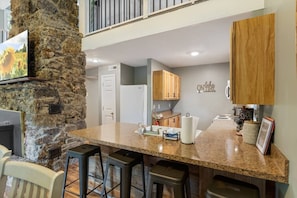 A kitchen with granite countertops, wooden cabinets, and a stone accent wall. - The Lake Front Oasis in Eldon•Near Bagnell Dam (Eldon)