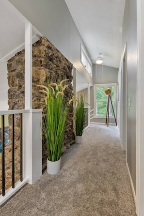 A hallway with a stone wall, potted plants, a tripod, and a window with a view. - The Lake Front Oasis in Eldon•Near Bagnell Dam (Eldon)