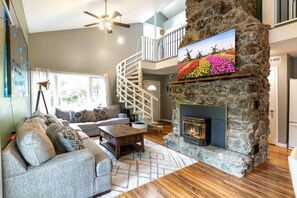 A cozy living room with a stone fireplace, a wooden coffee table, and a grey sofa. - The Lake Front Oasis in Eldon•Near Bagnell Dam (Eldon)